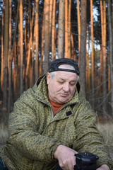 Naklejka na ściany i meble кавказский старик в осеннем лесу, изучает штатив для фотоаппарата