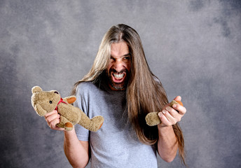 long haired man with broken teddy bear looking bad