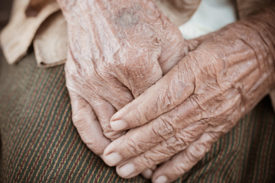 Hands Asian elderly woman grasps her hand on lap, pair of elderly wrinkled hands in prayer sitting alone in his house, World Kindness older and Adult care,  Mother day people concept