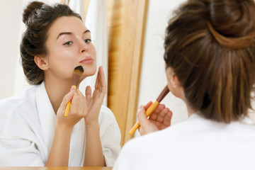 Obraz na płótnie Canvas Woman applying foundation or blusher on her face