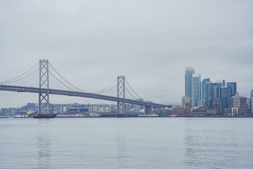 Fototapeta na wymiar The beautiful skyline of San Francisco with the Oakland Bay Bridge in a cloudy day