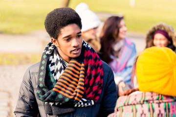 African American young man talking with a female friend outdoors in a winter day