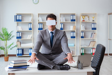 Businessman in virtual reality VR glasses meditating at desk top