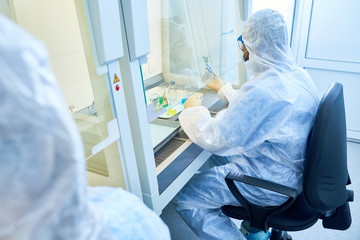 Back view portrait of unrecognizable scientist wearing protective suit and mask working with...