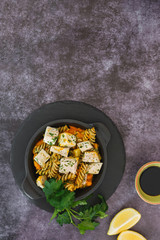 Fusilli pasta with smoked chicken, pumpkin and pesto. Top view, blank space, rustic background
