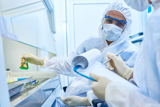 Portrait of two scientists wearing protective suits and masks working with hazardous materials in medical research laboratory