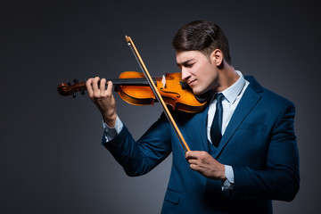 Young man playing violin in dark room