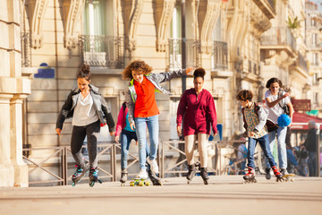 Happy teenage boys and girls rollerblading in city