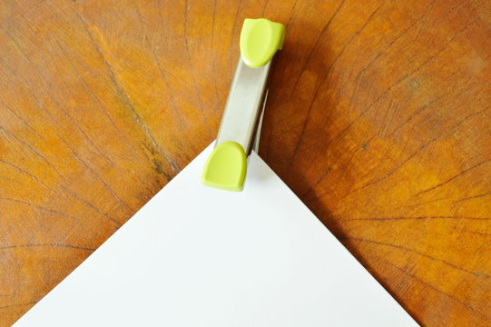 stapler pushing white paper on wooden table