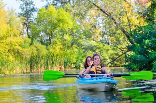 Family kayaking sport, mother and child paddling in kayak on river canoe tour, active autumn weekend and vacation, fitness concept
