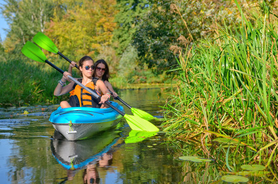 Family kayaking sport, mother and child paddling in kayak on river canoe tour, active autumn weekend and vacation, fitness concept
