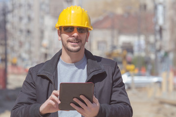 Construction worker posing with his tablet outdoors.