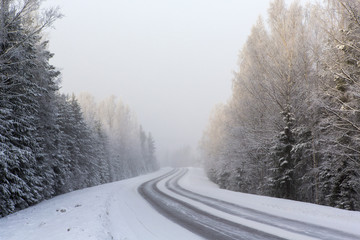 Winding and wintry road in Finland. Curves with snow covered asphalt road. Empty highway for traveling.