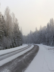 Obraz premium Winding and wintry road in Finland. Curves with snow covered asphalt road. Empty highway for traveling.