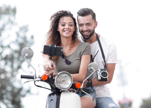 Male and female on motor scooters in a town.