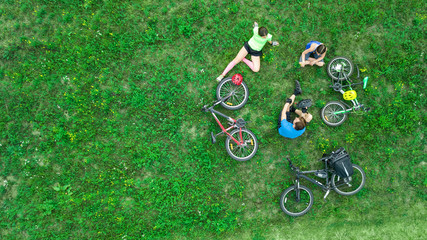 Family cycling on bikes outdoors aerial view from above, happy active parents with child have fun and relax on grass, family sport and fitness on weekend
