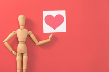 Wooden man figure holding red heart. Concept for valentine's day.