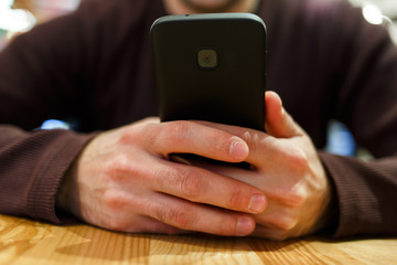 Photo of man with smartphone in hands, sitting at table