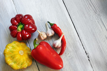 Red, yellow and green bush pumpkins, peppers, garlic on white wood background. Garden,agriculture and farming concept.