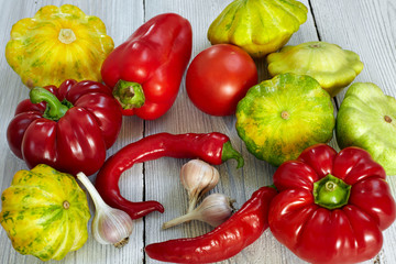 Fresh organic vegetables as a background. Red, yellow and green bush pumpkins, peppers, garlic on white wood background. Garden,agriculture and farming concept.