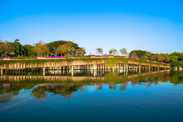 Fototapeta na wymiar Stone Bridge in a park with lake on blue sky