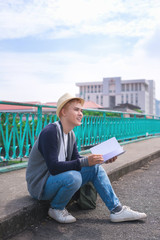 Fototapeta na wymiar Young Asian reading book while siting on city walking brigde.