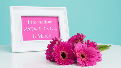 Happy Women's Day Pastel Candy Blue Coloured Background with Dark pink gerberas ion the table and...
