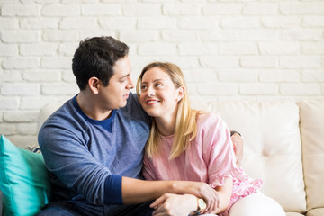 Loving young couple sitting on couch at home