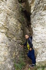 A cheerful little boy traveler stands in the crevice of the rock.