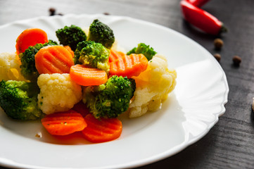Mixed vegetables. cauliflower, broccoli and carrots in plate on a dark wooden background