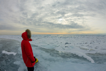 women in a red parka jacket with a fur hood in a snowy Baikal in the hummocks