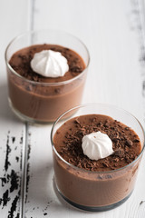 Chocolate mousse in a glasses on a white wood background.