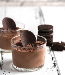 Chocolate mousse in a glasses on a white wood background.