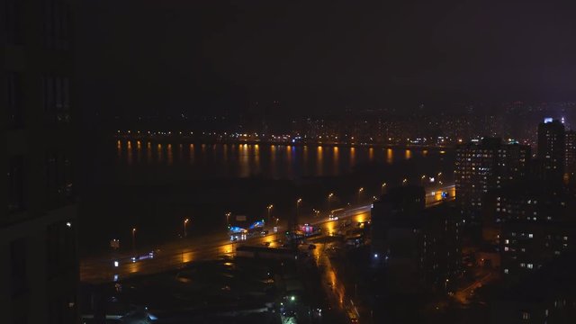 shooting night city. The lights are burning in the windows of apartment buildings. On the asphalt reflections glare from the passing cars. light is splashing in the water. lake or river. night Kiev