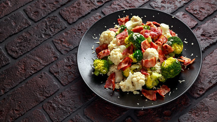 Steamed Broccoli, Cauliflower Salad with Bacon, parmesan cheese in a black plate. healthy food concept