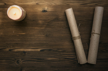 Scroll paper page and a candle on wooden desk table background with copy space, top view. Education background. Back to school concept.