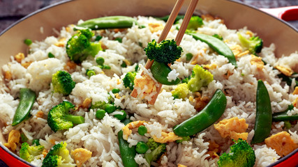 Fried rice with vegetables, broccoli, peas and eggs served in a pan. healthy food