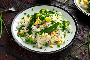 Fried rice with vegetables, broccoli, peas and eggs in a plate. soy sauce. healthy food