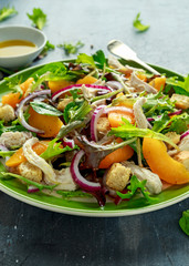 Fresh salad with chicken breast, peach, red onion, croutons and vegetables in a green plate. healthy food