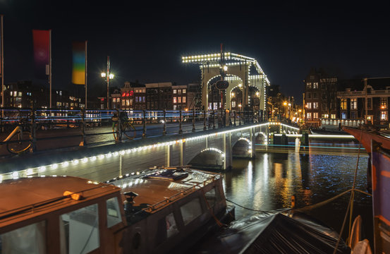 The Magere Bridge over the river Amstel with in the background the characteristic canals buildings in the old center of Amsterdam.