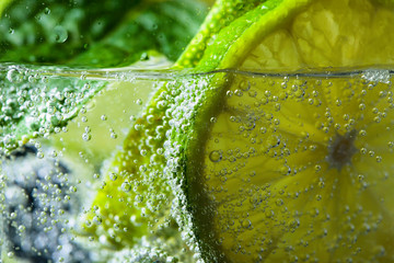 Close up of cocktail with lime , ice  and mint  .