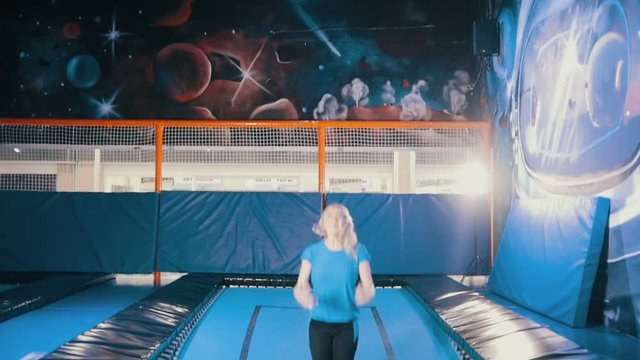 Young attractive athletic girl jumping on a trampoline, performing acrobatics, stretching, splits the air in the sports centre