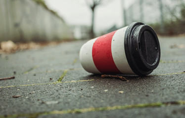 Weggeworfener leerer Kaffeebecher liegt auf Gehweg.