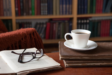 Sweet moments of relaxation with books and a cup of coffee. Vintage books, glasses, chair, library