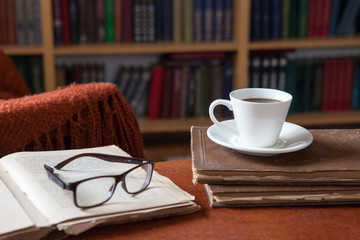 Sweet moments of relaxation with books and a cup of coffee. Vintage books, glasses, chair, library