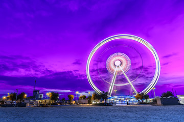 Spinning ferris wheel at sunrise blue hour in Rimini, Italy. Long exposure abstract image