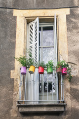 Balcony in the town Viviers decorated with painted cans filled with plants