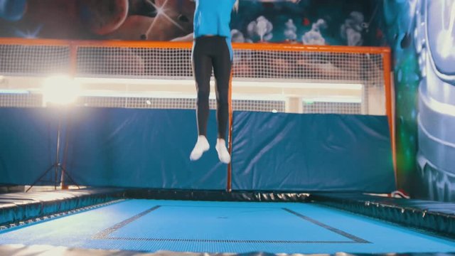 Young attractive athletic girl jumping on a trampoline in the sports centre, pushes away and lands in different parts of the body