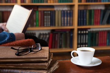 Sweet moments of relaxation with books and a cup of coffee. Vintage books, glasses, chair, library, man