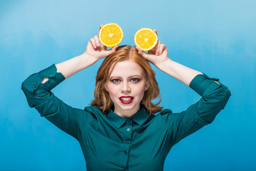 happy beautiful joyful red haired girl with makeup on a blue background smiling with orange on the head. positive emotions, laughter, happiness, messing around. Ears